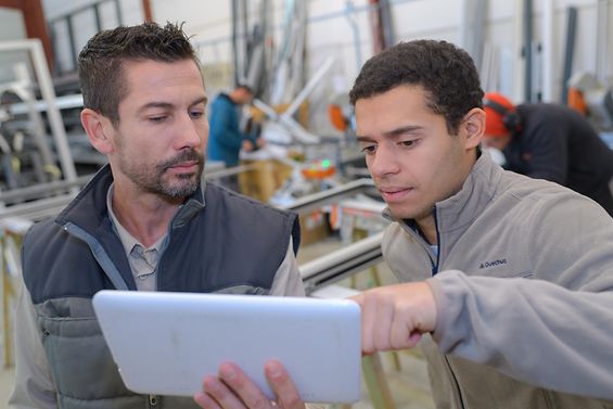 Zwei Männer in einem Betrieb betrachten einen Tablet-PC